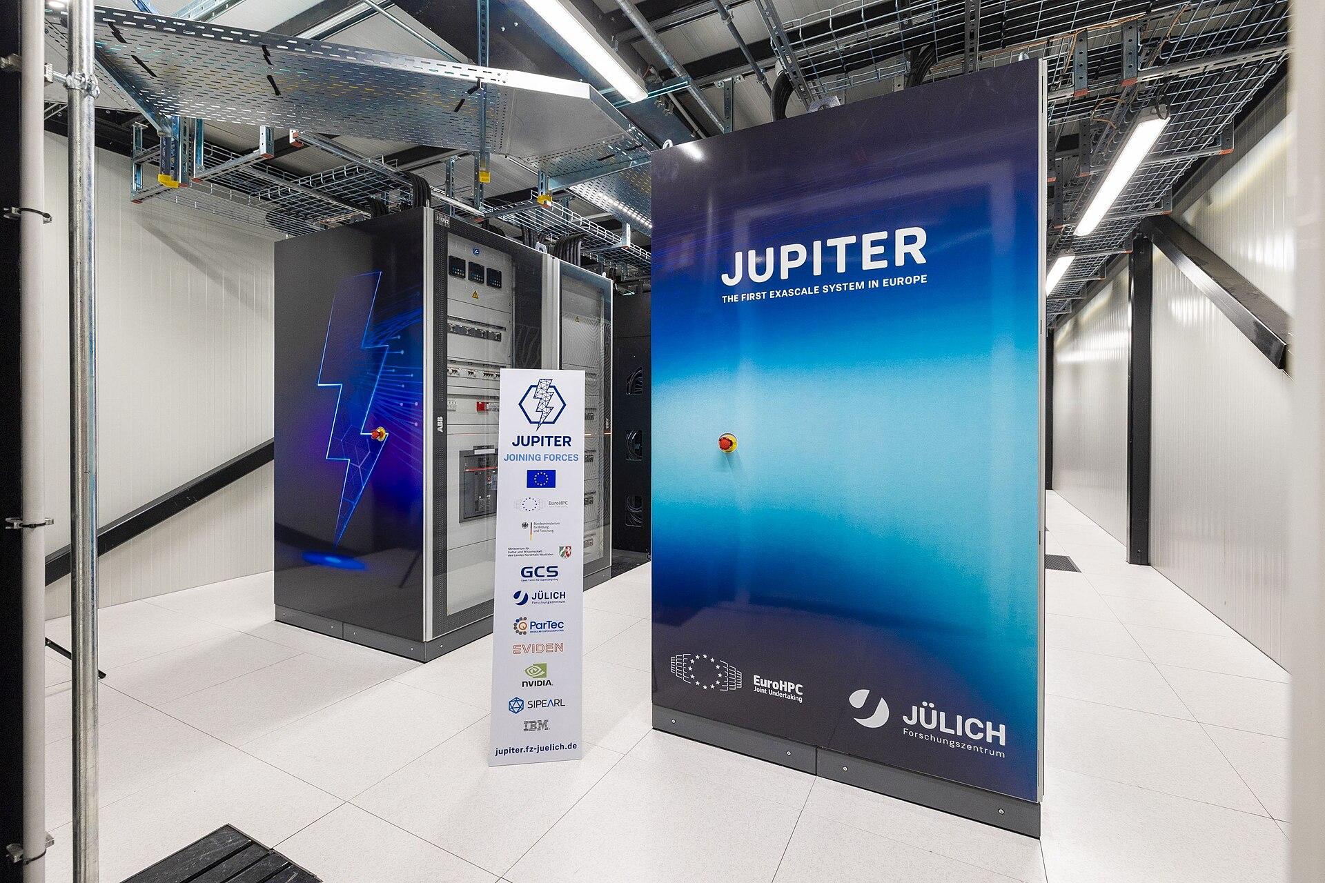 Racks do JUPITER, no Forschungszentrum Jülich, na Alemanha. É um dos sistemas exascale já entregues pelo EuroHPC, a mesma estrutura que agora licita as AI Gigafactories.
