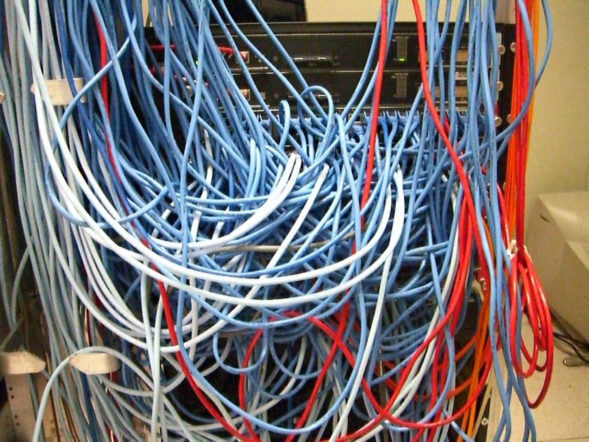 Cabos de rede em um rack de servidores. Imagem ilustrativa: o isolamento de rede é justamente o controle que falhou nos incidentes, e esta instalação não tem relação com os ambientes descritos pela Anthropic.